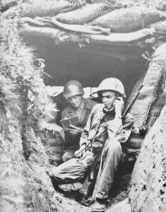 Lt. Funchess talks to headquarters from his dugout on the Kum River, July, 1950.