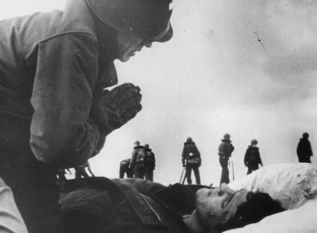 Father O’Callahan ministering to Robert C. Blanchard, March 19, 1945. Blanchard, who had passed out from smoke inhalation, awoke seconds later and survived the war. (PC: US Navy)