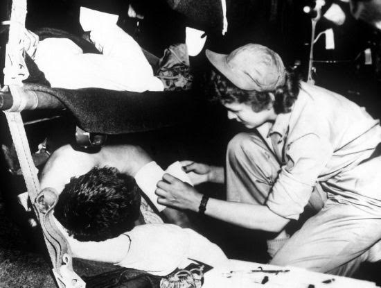Flight nurse 2nd Lt. Pauline Kircher dresses a patient’s wounds during the flight from Korea to Japan, May 1951.