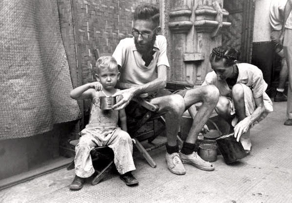 An emaciated father feeding Army rations to his son after he and his family were freed from a Japanese prison camp, Luzon, Philippines. February 05, 1945